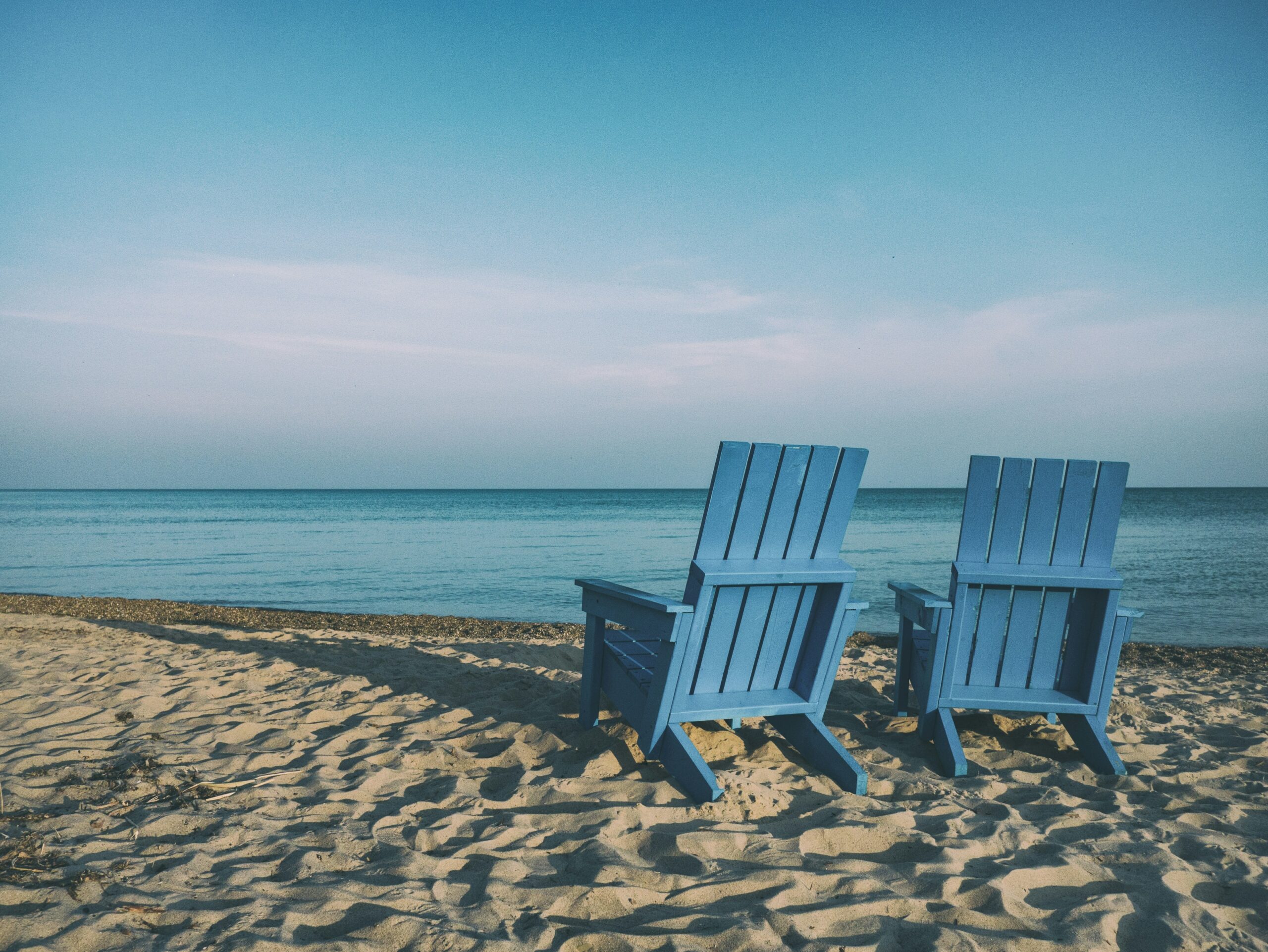 Blue chairs on beach overlooking the sea